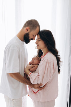 Newborn baby cradled by parents in soft natural light during quiet family moment