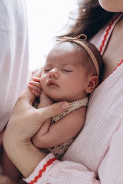 Newborn baby sleeping peacefully in gentle arms, wrapped in soft fabric with natural light