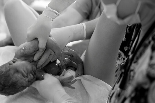 Newborn baby born in hospital held by mother and medical staff during quiet peaceful moment after birth