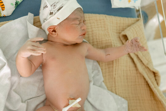Newborn baby sleeps peacefully in hospital bed wrapped in soft blankets