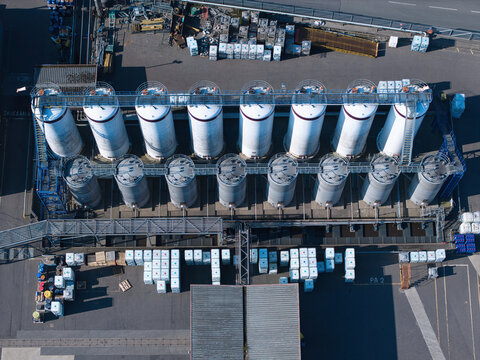 Aerial view of PD Ports industrial storage tanks and silos with connecting walkways and cargo pallets in an asphalt yard Scunthorpe, England, United Kingdom.