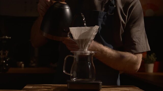 Barista pouring water with gooseneck kettle over V60, precision brewing, slow motion, warm sunlight and deep shadows.