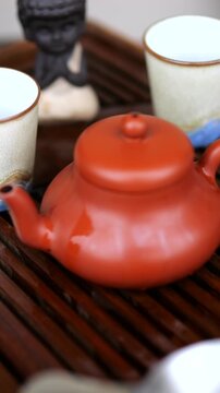 Clay teapot steaming on a wooden tea tray during a traditional gongfu cha ceremony, with small ceramic cups and a little monk figurine creating a mindful and serene atmosphere