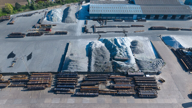 Aerial view of the PD Ports industrial facility featuring large piles of aggregate and organized stacks of steel beams under bright daylight in Scunthorpe, England, United Kingdom.