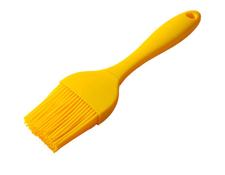A bright yellow silicone basting brush isolated on a solid black background