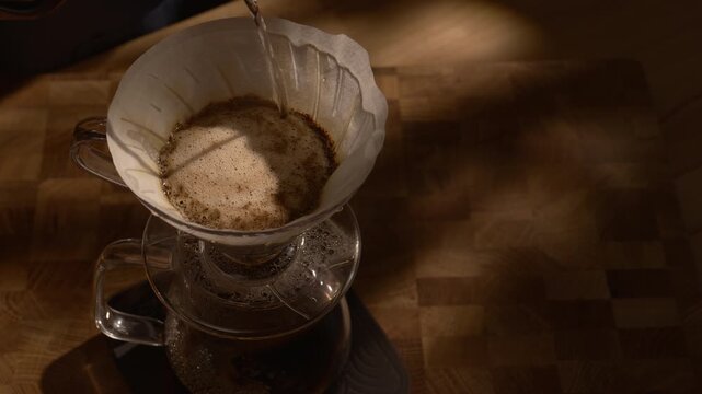 Barista pouring water with gooseneck kettle over V60, precision brewing, slow motion, warm sunlight and deep shadows.