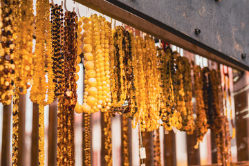 Amber necklace hanging on display in market stall. Collection of jewelry made from fossils beads. Accessory for fashion style and traditional decorative ornament. © Anton Dios