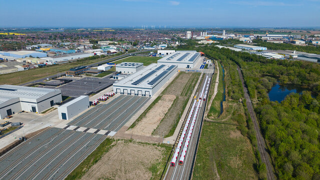 Aerial view of the industrial rail facility with modern warehouses, solar panels, and new trains parked on tracks in Goole, England, United Kingdom.