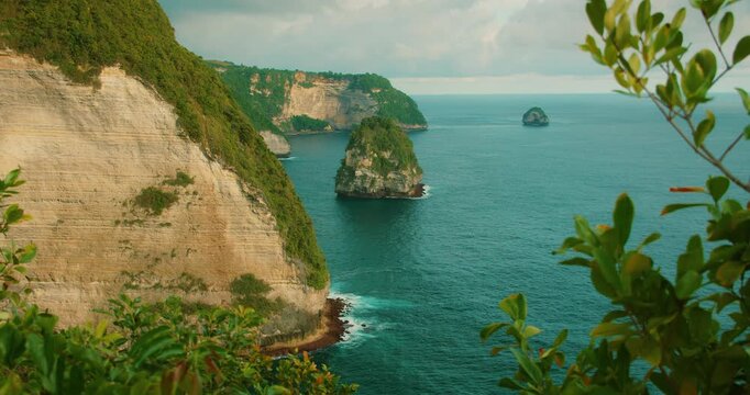 Distant rocky islands emerge from turquoise ocean water in Nusa Penida Bali