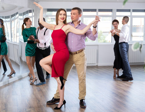 Happy woman enjoying passionate Latin American dancing with male partner in dance hall