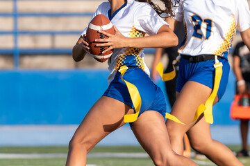 Flag football action view of a female flag football player carrying the ball while running with a teammate during a fast-paced outdoor game © Solomon Thompson