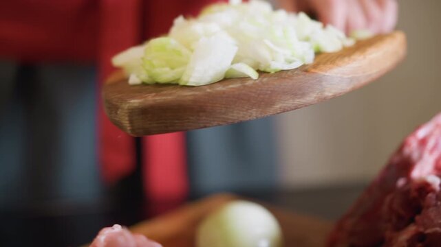 Preparing ingredients with careful motion. Domestic kitchen scene involving chopping and careful handling. Person skillfully slices onions into bowl following consistent and rhythmic pattern