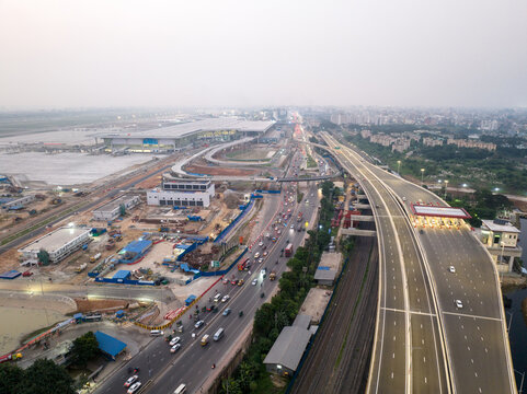 Aerial view of Hazrat Shahjalal International Airport terminal and the Dhaka Elevated Expressway with traffic and toll plaza under a hazy sky in Dhaka, Dhaka Division, Bangladesh.