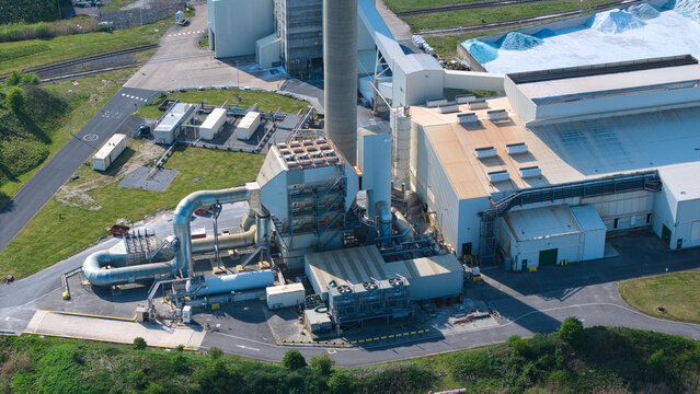 Aerial view of the Industrial Glass Manufacturing Facility featuring a tall chimney, complex piping systems, and large industrial warehouses in Goole, England, United Kingdom.
