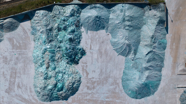 Aerial view of large piles of crushed recycled glass in shades of blue and green at an industrial glass manufacturing facility Goole, England, United Kingdom.
