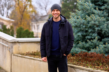Fototapeta premium Man smiles warmly, standing outdoors in autumn