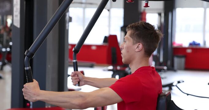 Man sweating while exercising with chest press machine in gym