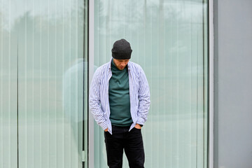 Young man stands pensively near glass wall © Iurii Gagarin