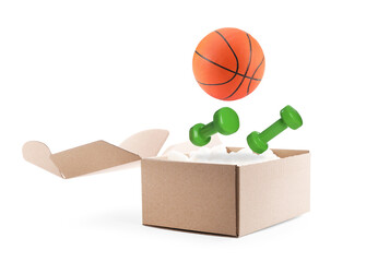 Basketball ball and dumbbells falling into cardboard box with styrofoam cubes on white background
