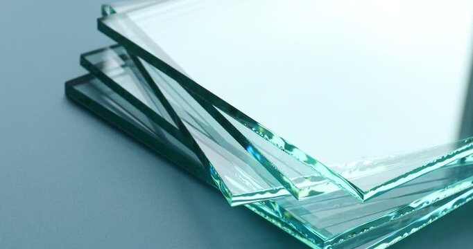 Stack of clean glass sheets turning on light blue background, closeup