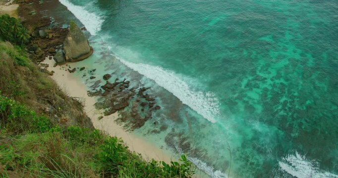 Crystal clear turquoise ocean water hitting sandy Diamond beach in Nusa Penida Bali