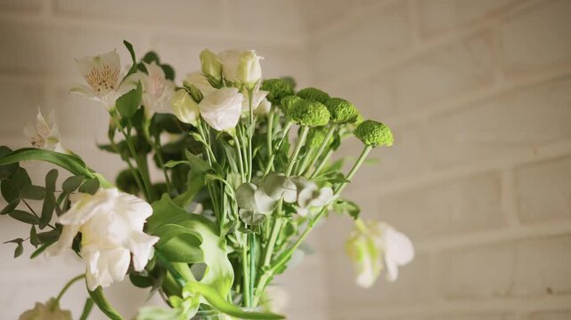 White rose bouquet on brick wall, cozy home kitchen vignette with soft sunlight illuminating delicate petals and green button mums in glass vase, rustic interior styling and slow living atmosphere