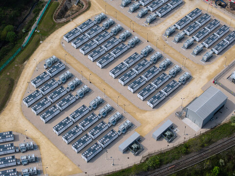 Aerial view of Battery Energy Storage Systems units arranged in rows on a gravel industrial site with surrounding greenery and infrastructure Knottingley, England, United Kingdom.