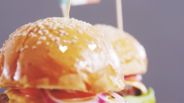 Focus landing on sesame bun flag, camera shifting down, hearts popping and fading showcasing burger