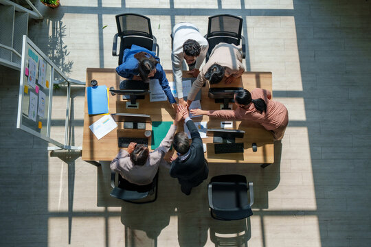 Teamwork collaboration unity office meeting strategy business model marketing ai drive dynamic team with hands together over laptop on table, overhead view with motivated trust and growth