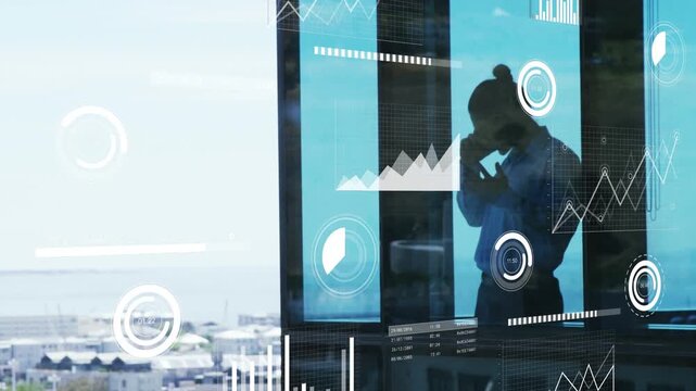 Businessperson receiving phone call beside window, reviewing animated charts reflected on glass