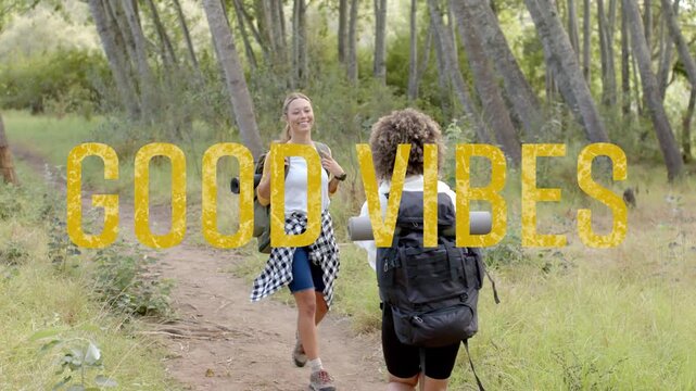 2 women hiking trail spotting reuniting lifting phone sharing moment with yellow GOOD VIBES overlay