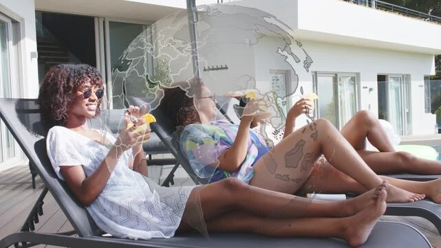 Three women sitting and lifting drinks, toasting poolside for lifestyle promo, globe covering group