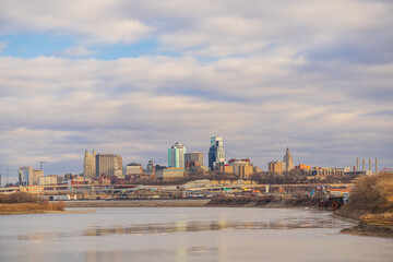 Fototapeta premium The skyline of Kansas City rises above the river under a cloudy sky.