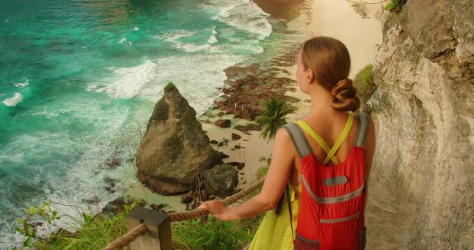 Woman overlooking Diamond Beach ocean from cliff path in Nusa Penida Bali Island