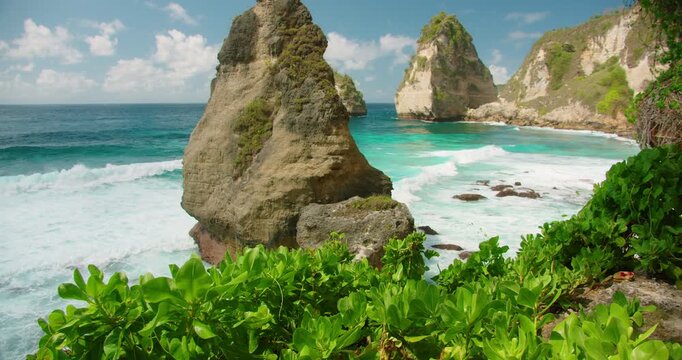 Steep limestone stacks emerge from vibrant blue sea water along Nusa Penida shoreline