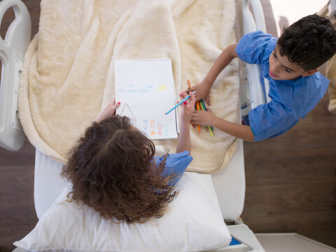 Children drawing together in a Middle Eastern hospital bed while receiving pediatric care and support