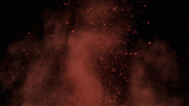 Red particles exploding in darkness.
