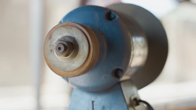 Close up blue grinder spindle rust, workshop scene with soft natural light, shallow depth of field, worn metal collar and thread, carpenter preparing tool for sharpening, warm vintage tones