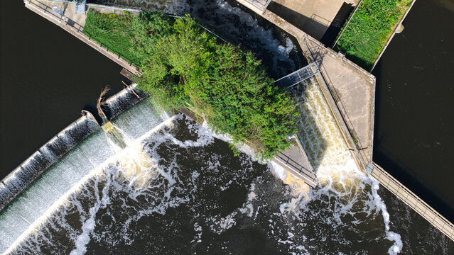 Aerial view of Knottingley Weir and Hydroelectric Power Plant with rushing water and a small green island Knottingley, England, United Kingdom.