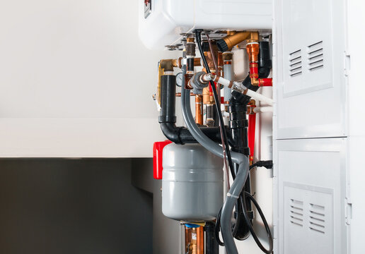 Plumbing underneath hot water heating system. Piping for a natural gas&ndash;powered heater in a closed-loop hydronic system. Plumbing service for home heating and maintaining. Selective focus.
