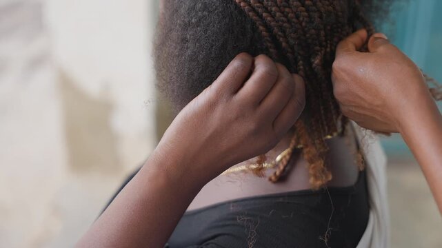 Close shot of hair weaving. Focus on fingers and roots during professional hair braiding process. Precise finger work in natural lighting capturing intricate hair weaving craftsmanship