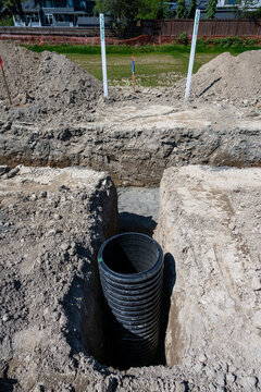 Septic Tank Riser, large black plastic corrugated pipe, installed in trench dug out in dirt of housing development construction project, site preparation detail earthwork

