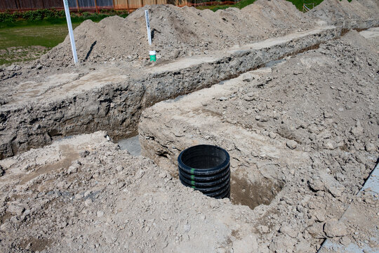 Septic Tank Riser, large black plastic corrugated pipe, installed in trench dug out in dirt of housing development construction project, site preparation detail earthwork
