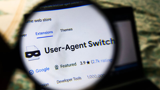 Closeup of a magnifying glass over a computer screen showing the useragent switcher browser extension in the chrome web store