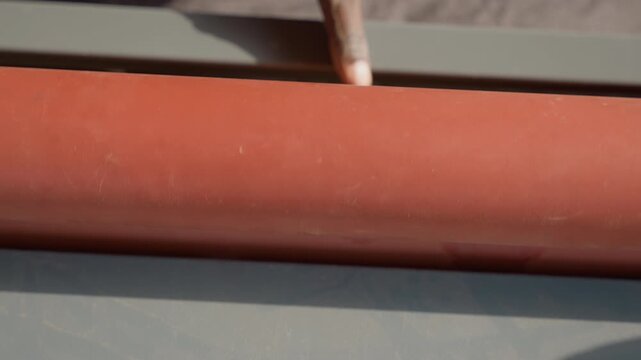 Closeup sanding drum inspection with finger, dusty red abrasive roll on bench, subtle scratches visible, craftsman testing texture, workshop sunlight highlighting dust, quality control moment