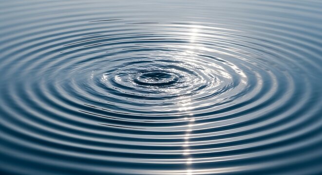 Concentric water ripples on blue liquid surface, tranquil circular wave patterns, serene water drop impact with soft sunlight reflections
