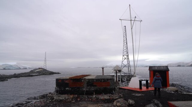 A stationary view of the communication masts and industrial facilities at Melchior Base, an Argentine research station in the Melchior Islands, featuring heavy polar wind noise