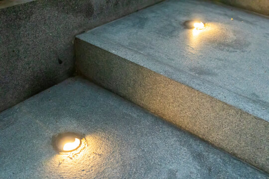 Close-up of recessed floor lights on granite outdoor stairs at night for safety and walkway illumination.