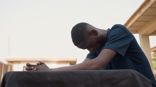 Laborer pauses activity. Worker stops work momentarily outside. Man resting outdoors after finishing his work for day. Worker sits and recovers during twilight after completing his tasks outside