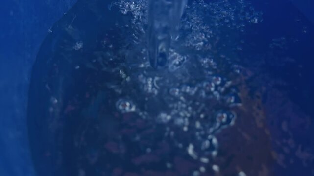 Bubbling blue liquid churning in bucket, dynamic aeration and bubble formation during rapid pour, bright highlights on wet surface, closeup texture study for carpentry finish demo